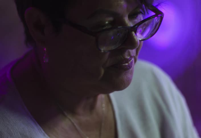 A woman with short brown hair talks and then adjusts her glasses