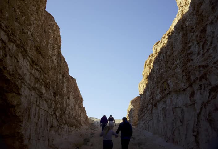 A small group of hikers ascend a narrow gorge on a sunny day