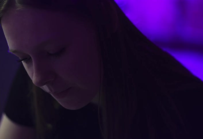 Woman concentrates on a task while in a room lit by purple lighting