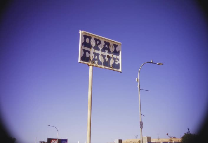 Tall sign for the opal cave stands next to a streetlight on a sunny day