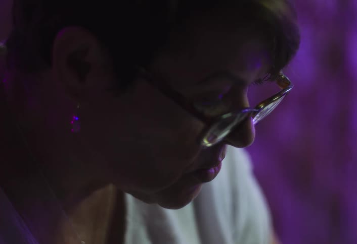 Woman wearing glasses focused under soft purple light
