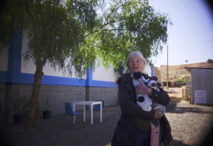The woman is holding her puppies outside