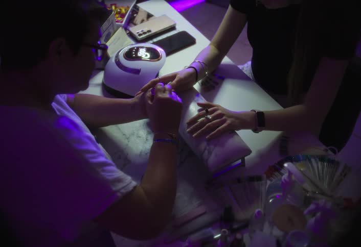 A manicurist applies nail polish to a customers hand in a salon