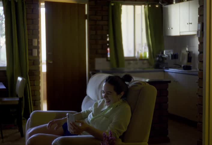 The woman is talking on her phone at home