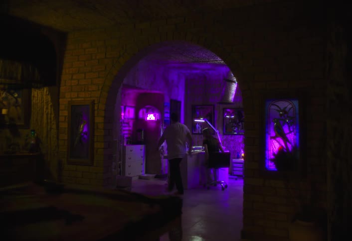 Room illuminated by purple lights where two people talk in an office