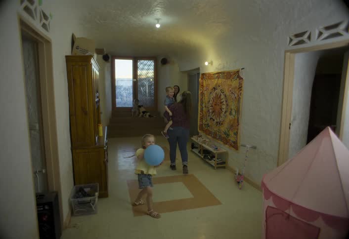 Mother picks up her son and is followed by her daughter through a room