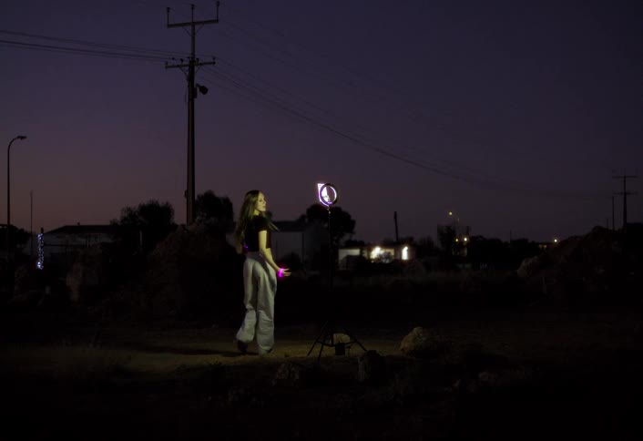 The girl is recording herself outside at night