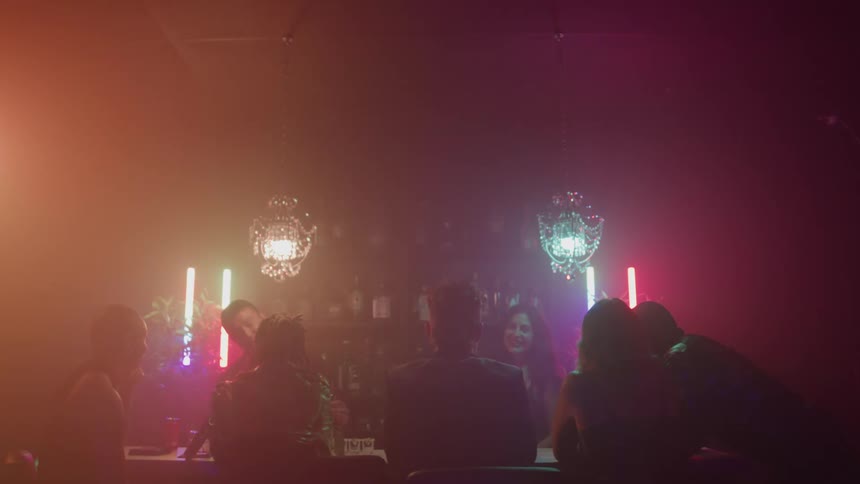 People are talking and drinking in the foggy nightclub