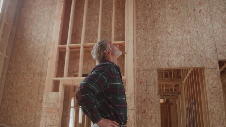 The man looks up at the home under construction