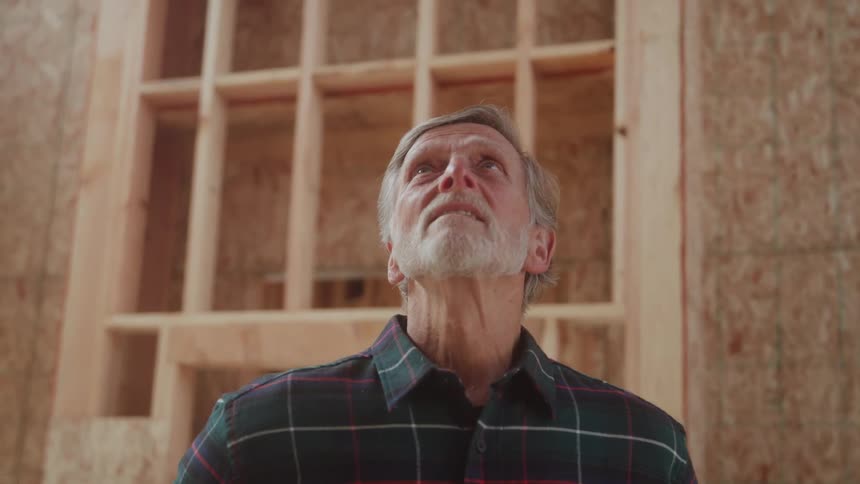 The man is looking up inside the homes frame