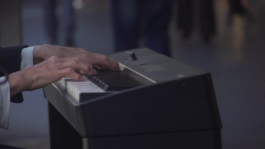 Person playing piano on sidewalk