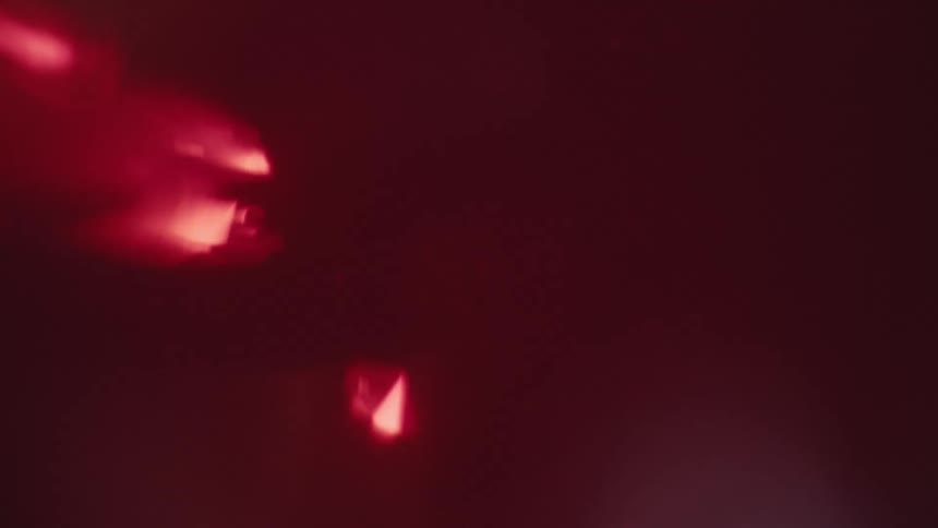 Several abstract diamond red bokeh light shapes float and move across a dark burgundy background creating a soft out of focus atmosphere