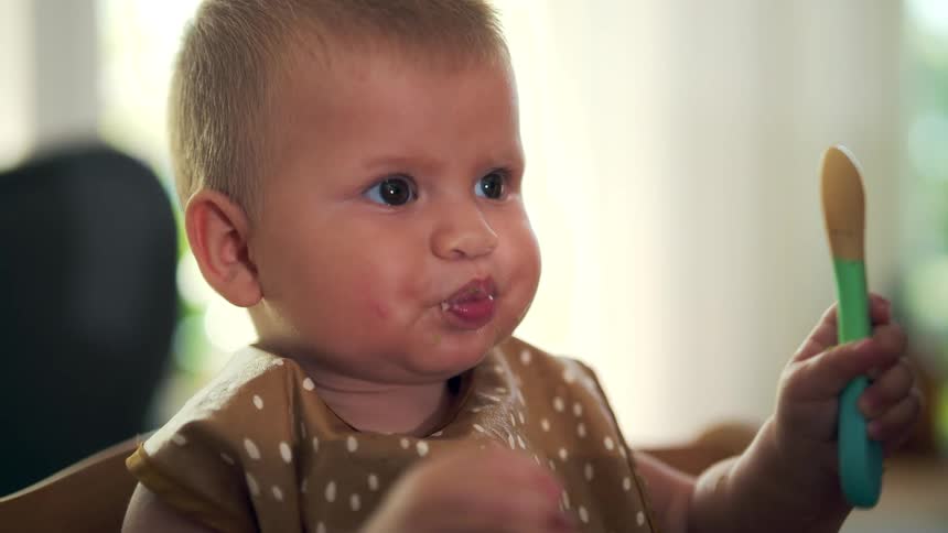 The baby swings his food and eats
