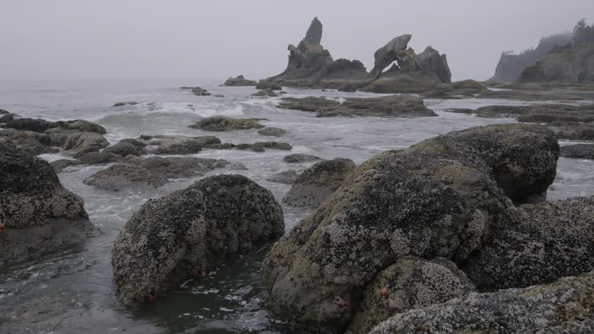 Ocean waves crash into large boulders