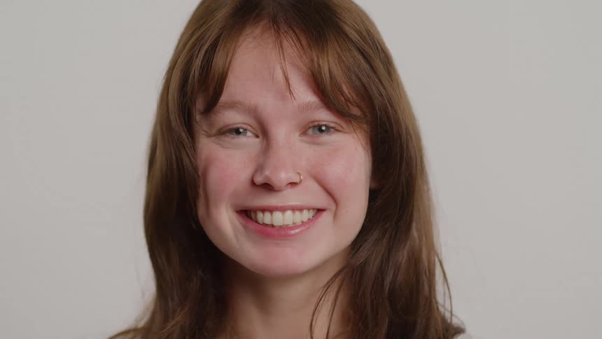 The face of a blueeyed woman staring straight ahead with a wide smile on her face