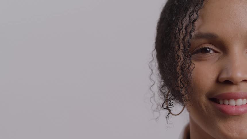 A young black woman with long curly hair smiling showing her teeth at midday