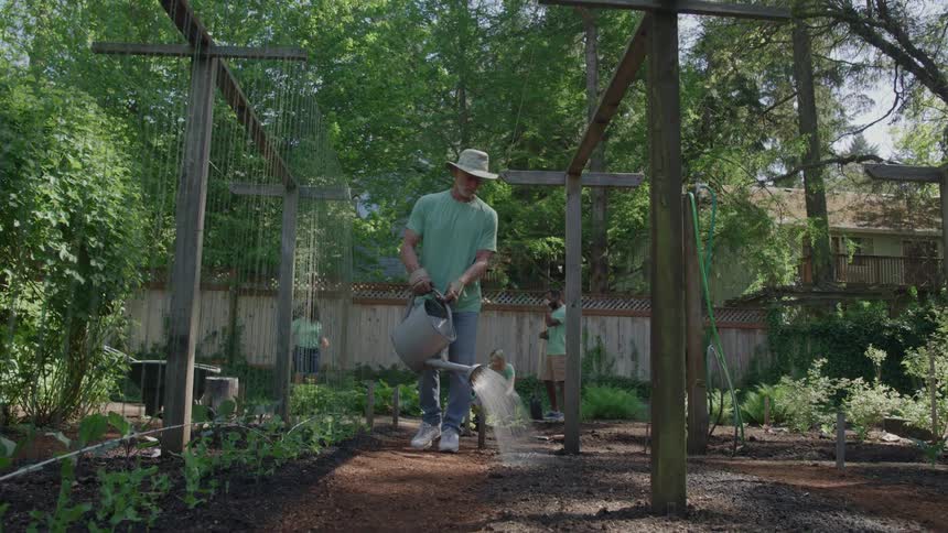A group of people watering plants in a garden