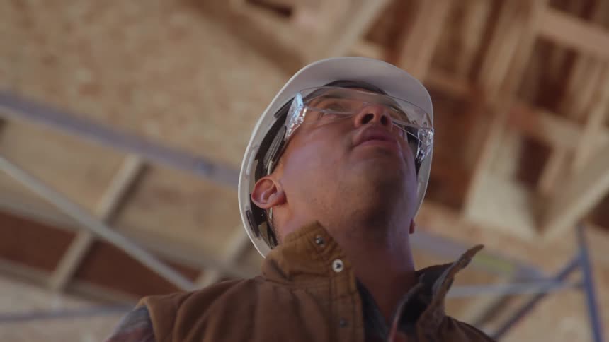 Close up of a young black male construction worker inspecting a building ceiling during daytime