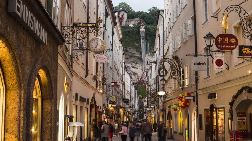 A time laps of people walking along a row of buildings with shops in them