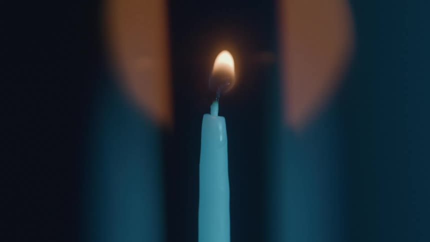 A persons hand using a match to light a white candle