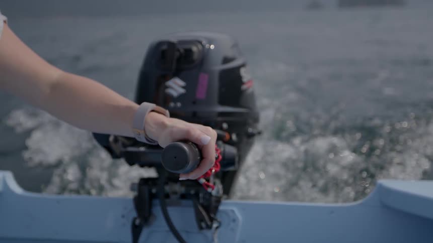 A person steers the boat with the tiller