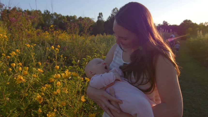 The mother holds her baby on the field