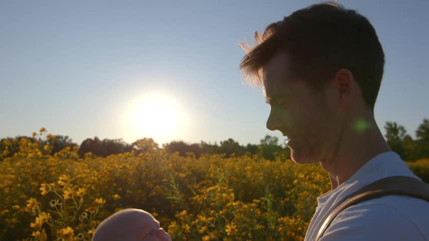 A father holding a baby in a field of flowers