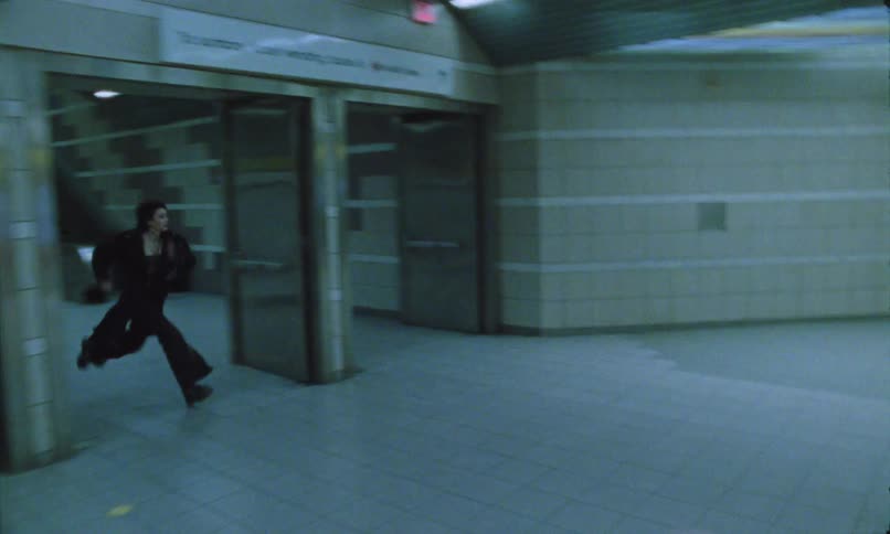 A man and a woman running in a subway station