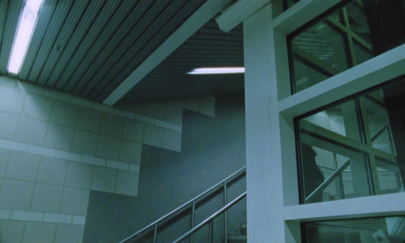 Two men quickly descending stairs in a coldlooking building