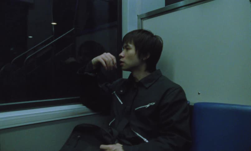 A young asian man sitting in a moving train at night