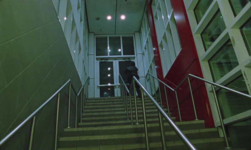 A man running up the stairs with steel railings at night
