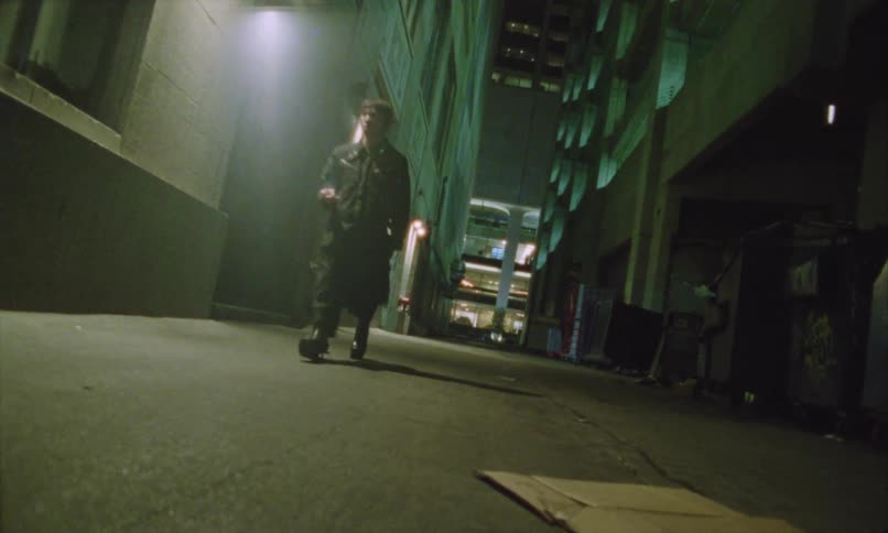 Man smokes while walking through a city alley at night