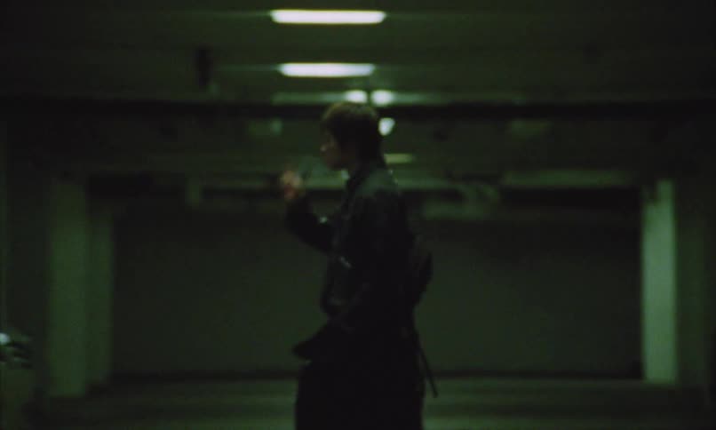 Man walks in an underground parking lot while smoking