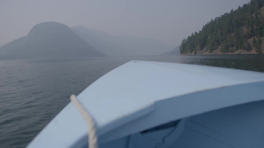 A boat moves in the foggy water