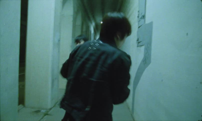 Two young men fight in a narrow dimly lit hallway