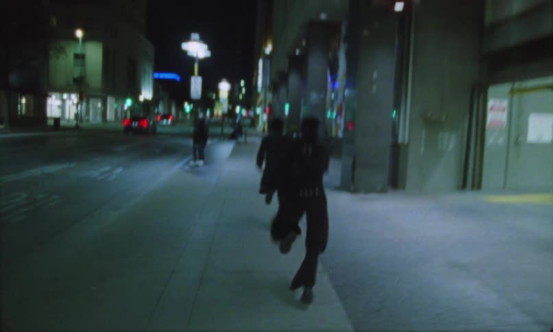 The woman chases a man through the city at night
