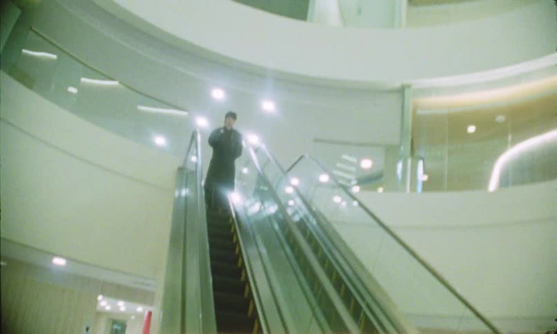 A young woman with a backpack descending an escalator