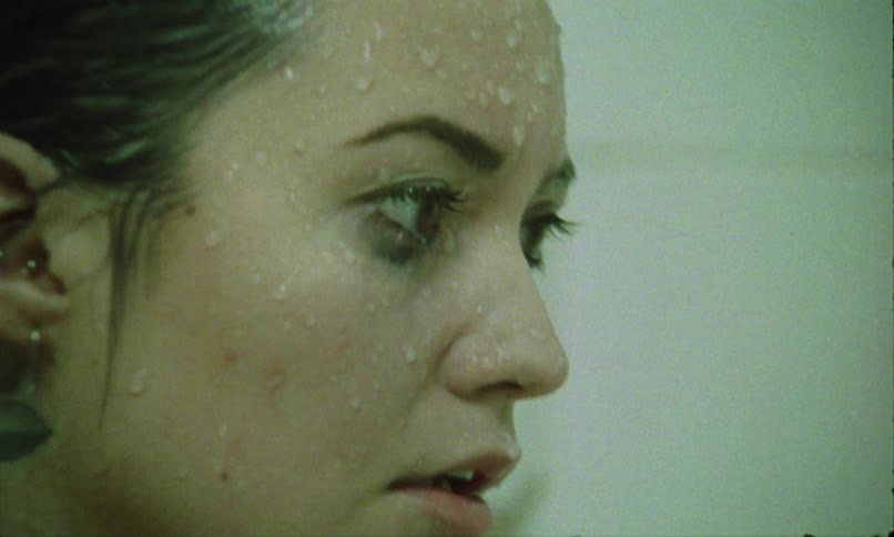 Woman with a wet face staring at something with a tense expression