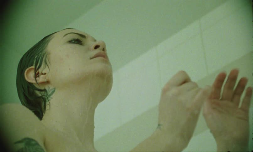 Woman with multiple tattoos rinses her face and head