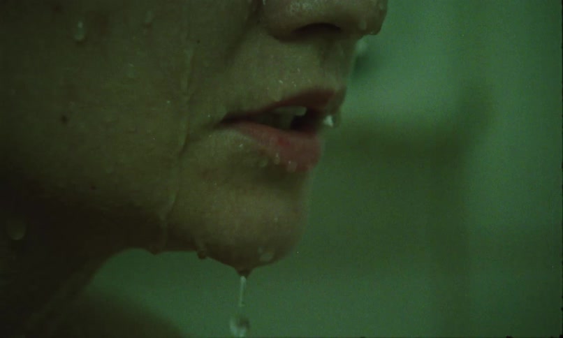 A close profile of a wet face shows water streaming down their lips and chin