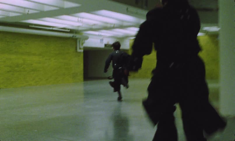 Person running while being chased in a brightly lit corridor
