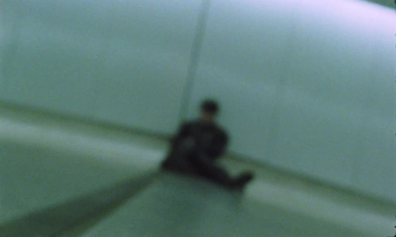 The man is sitting against the wall in the subway