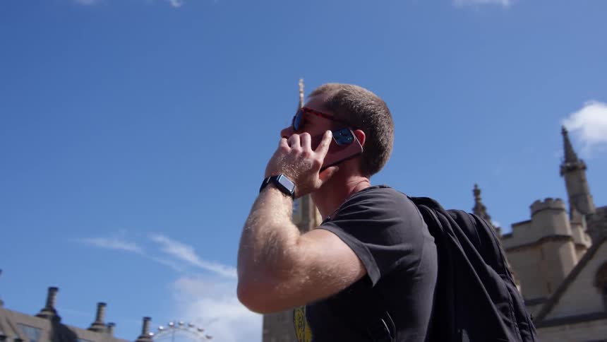 A man is standing outside a castle talking on his phone