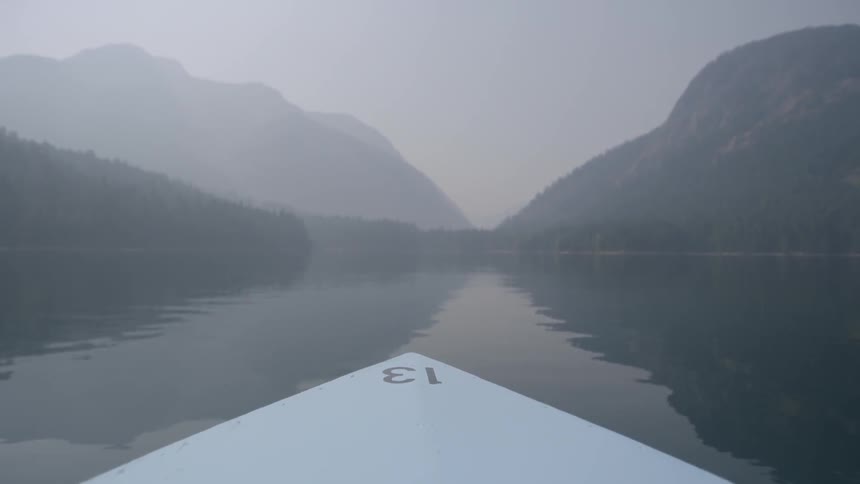 Boat traveling on a lake in the mountains on overcast day