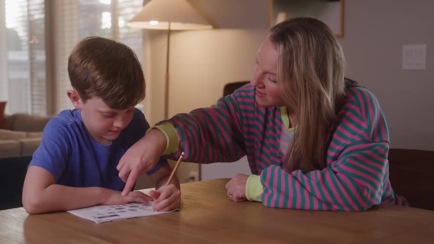Parent assisting young child with homework at a table