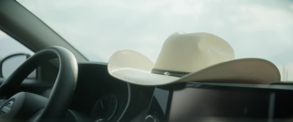 White cowboy hat sitting on dashboard while car is driving