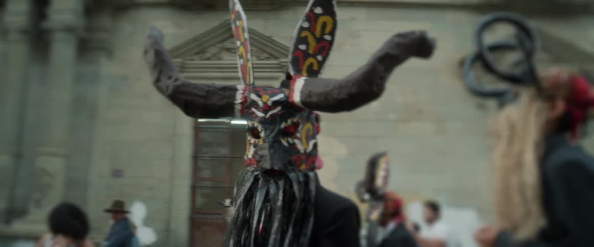 A person wearing a black costume while parading during a city festival in daytime