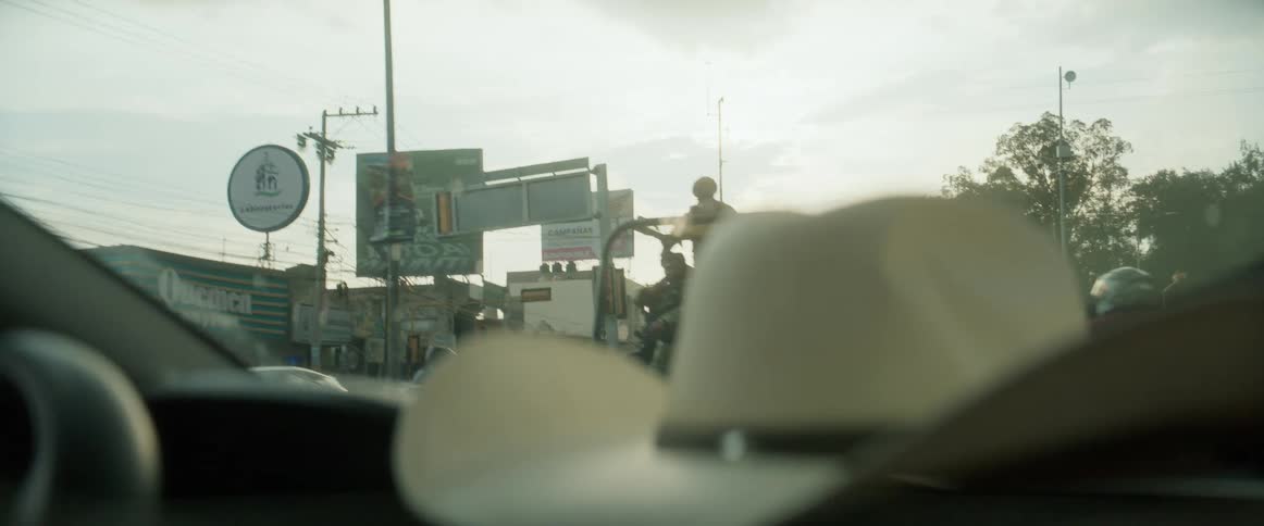 Armed soldiers ride in an open vehicle seen from inside a car
