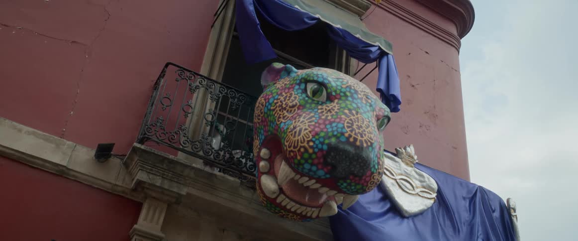 A decoration shaped like a animal head hangs from a balcony