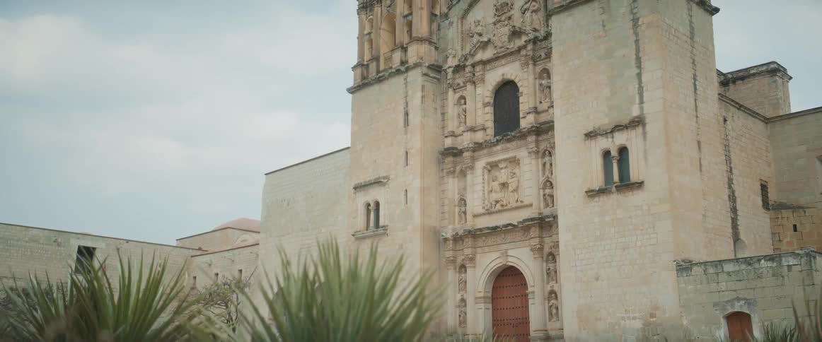 Historic stone mission building with desert plants in front